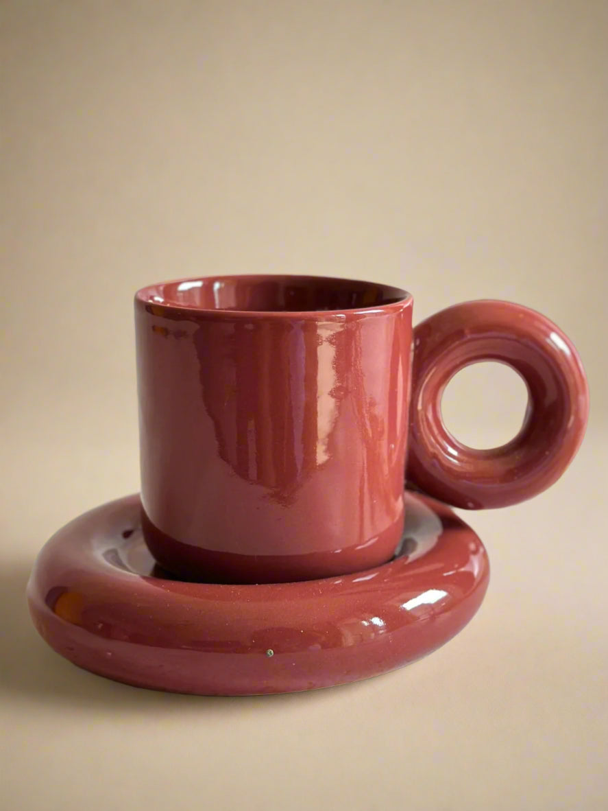 a couple of red cups and saucers on a table