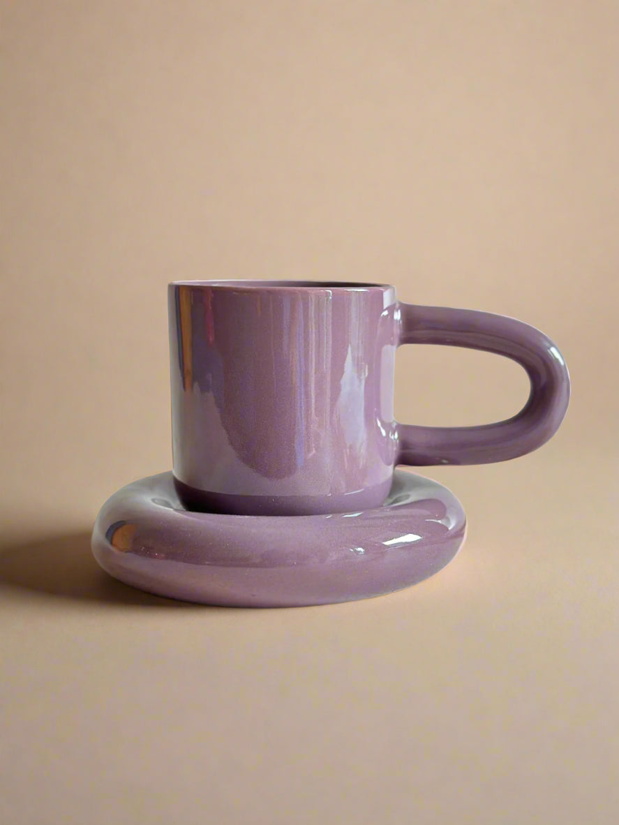 a purple coffee cup sitting on top of a saucer