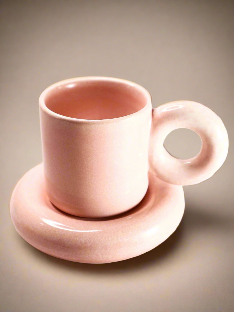 a pink cup and saucer sitting on a table