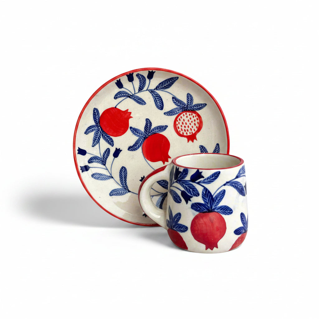 A ceramic plate and mug set with a red and blue pomegranate design on a white background.