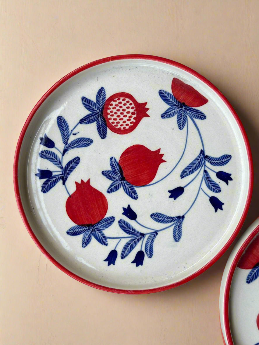 Decorative plate with red pomegranate and blue floral patterns on a beige background
