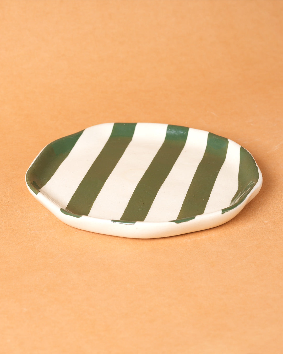 Green and white striped ceramic plate on a beige background
