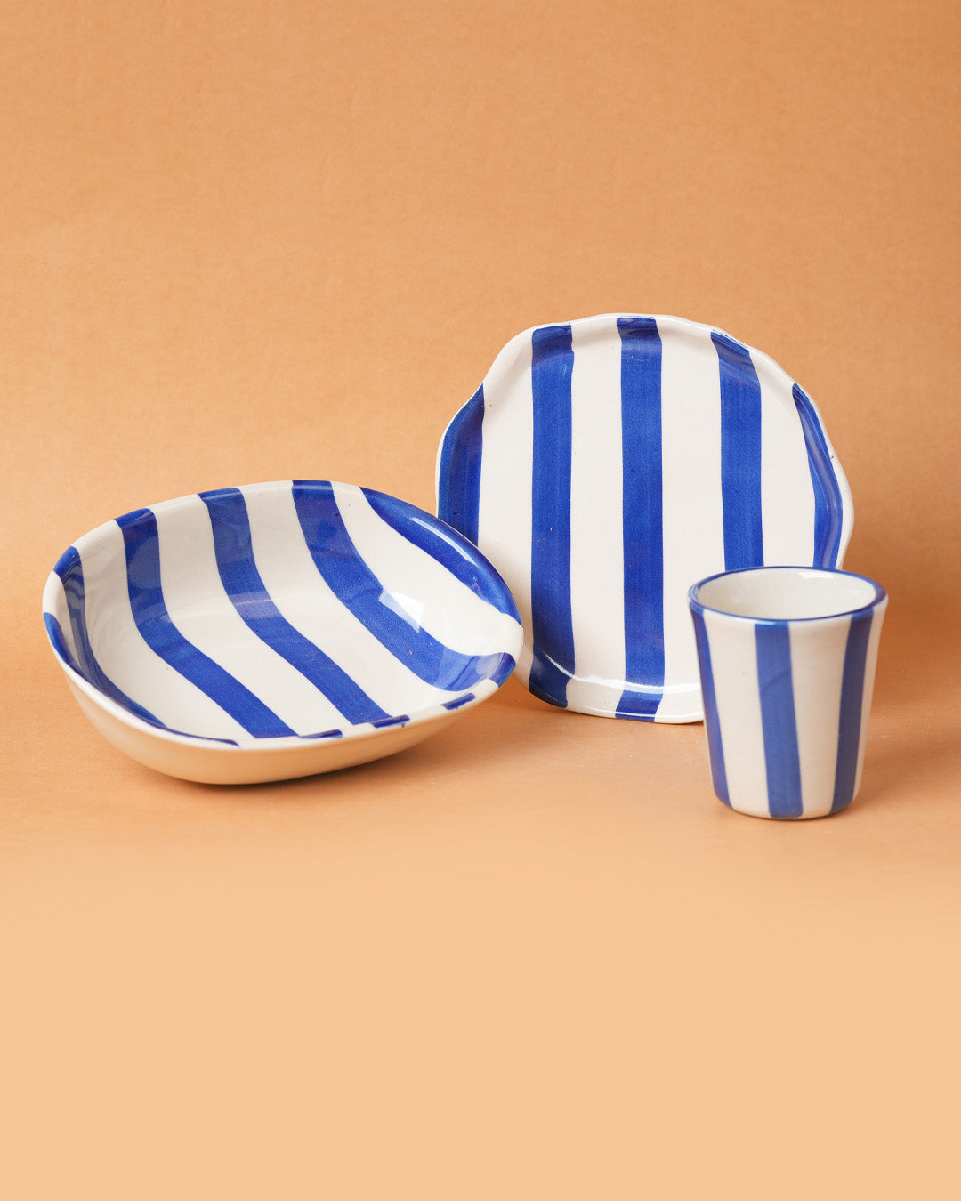 Ceramic tableware set with blue and white stripes on a beige background