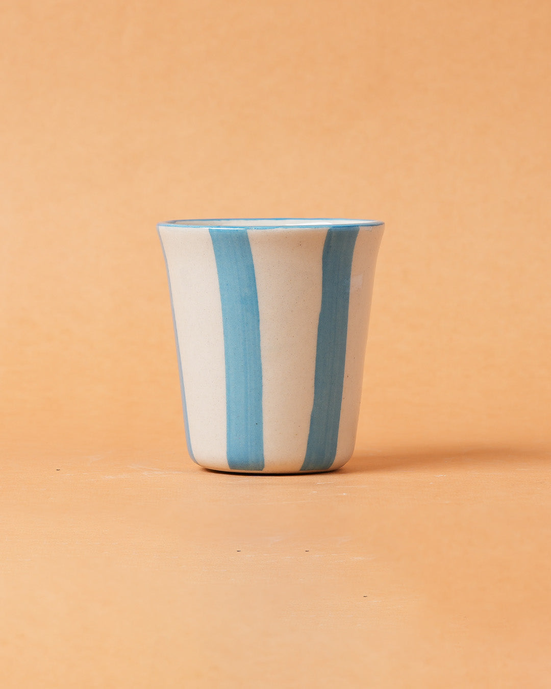 Ceramic cup with blue stripes on a beige background