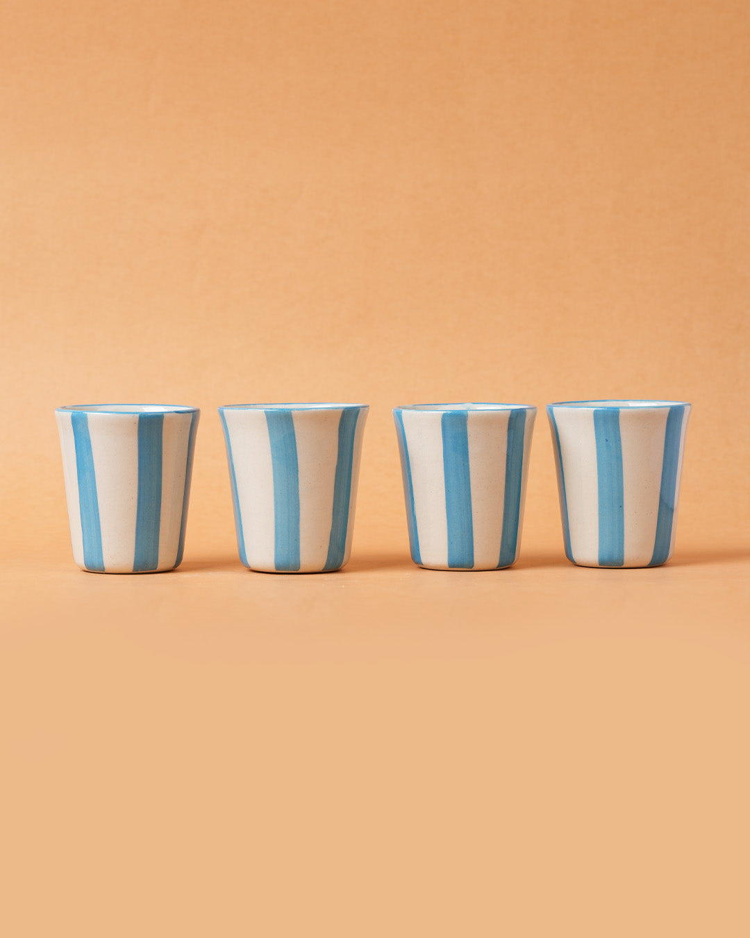 Four striped ceramic cups on a beige background