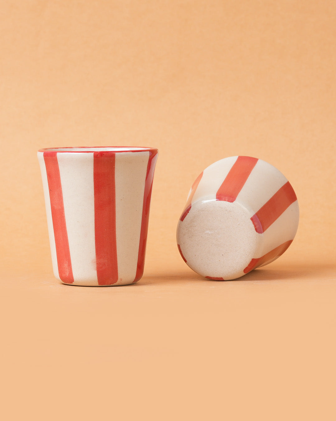 Ceramic cup with red and white stripes on a beige background