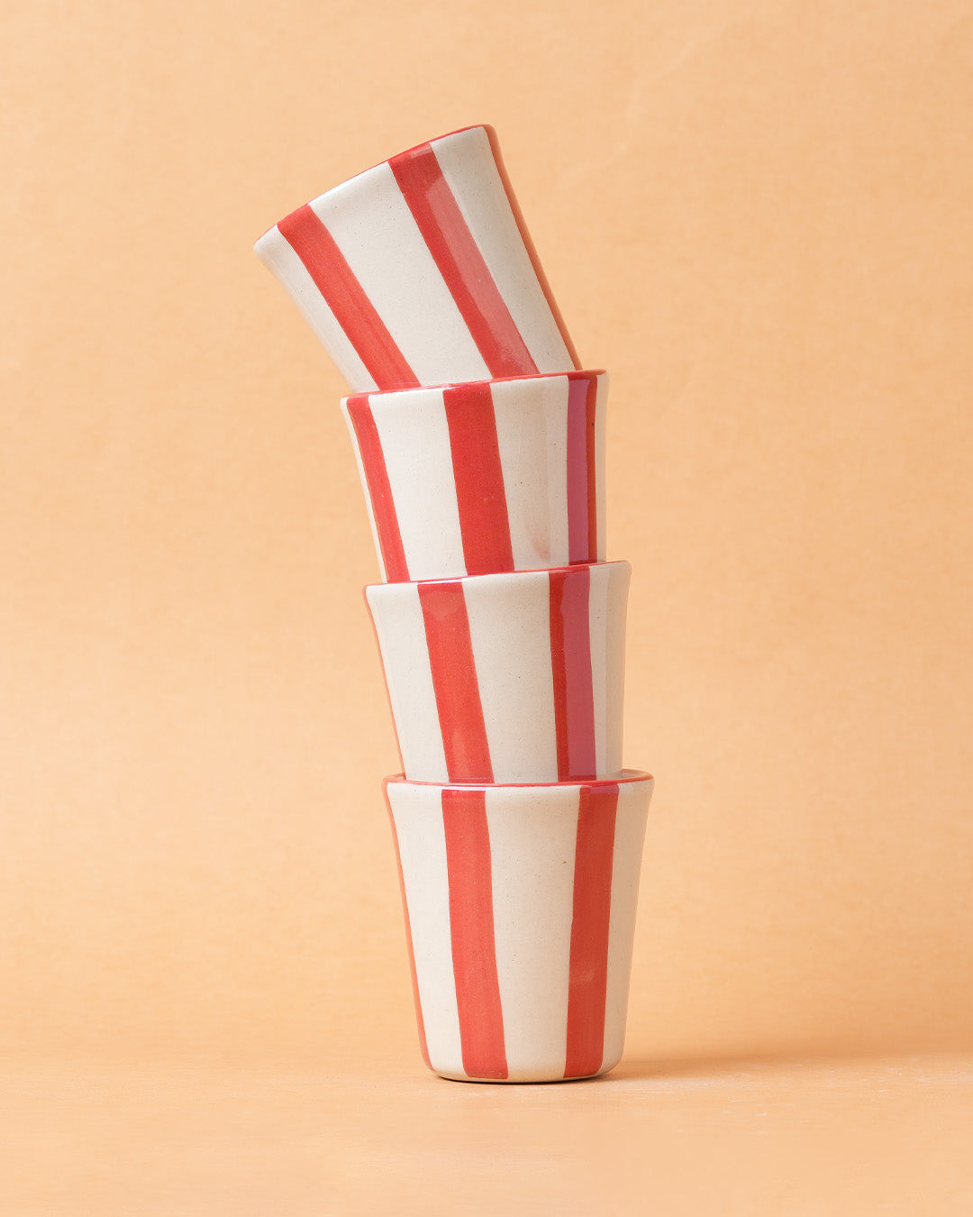 Stack of red and white striped ceramic bowls on a beige background