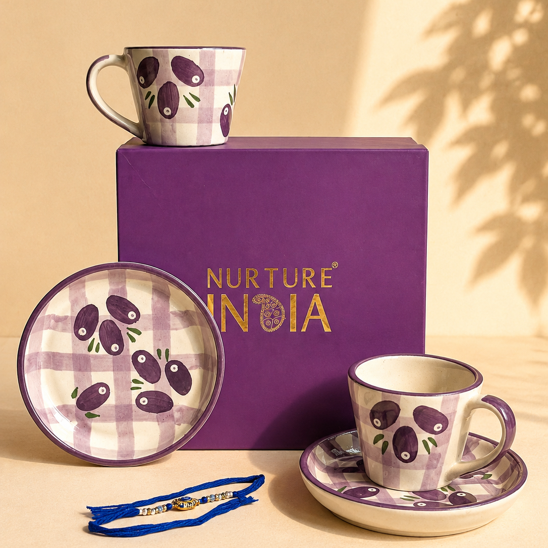 Nurture Nodia ceramic tableware set featuring a purple and cream gingham pattern with olive illustrations, including a mug, plate, cup on saucer, and a blue string accessory, arranged around a purple gift box on a beige surface.