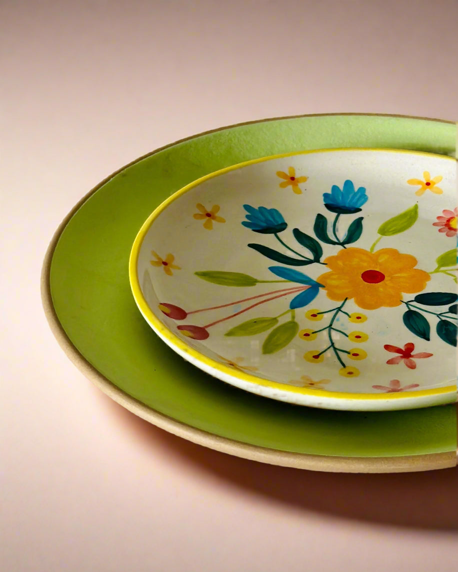 Stack of ceramic plates with floral design on a light pink background
