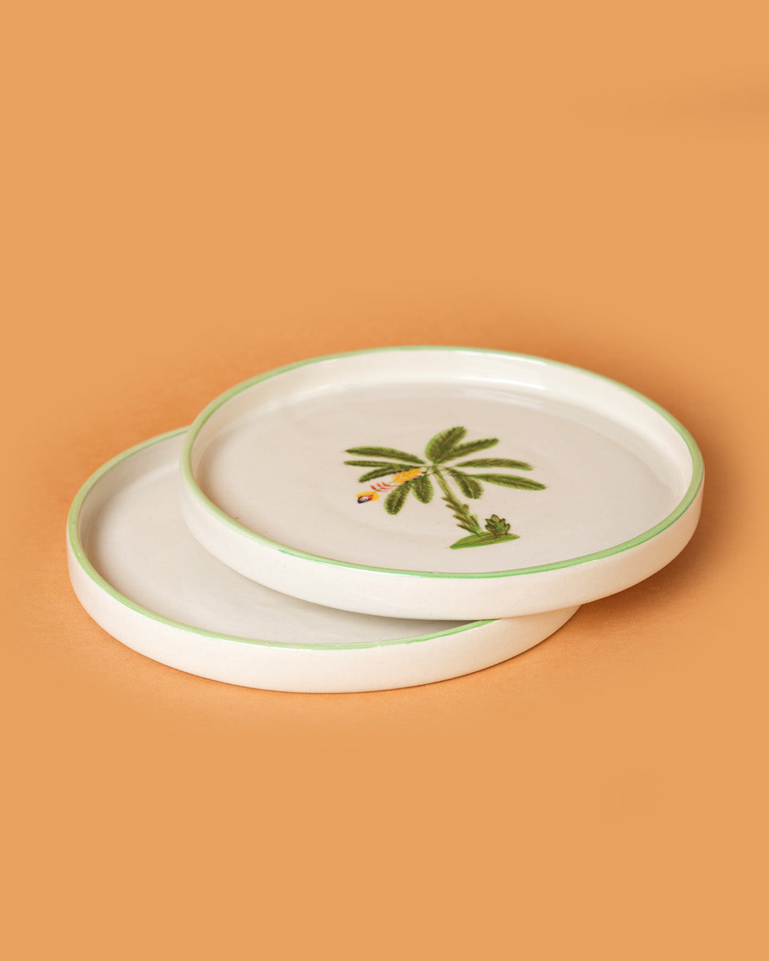 Two ceramic plates with palm tree design on a beige background