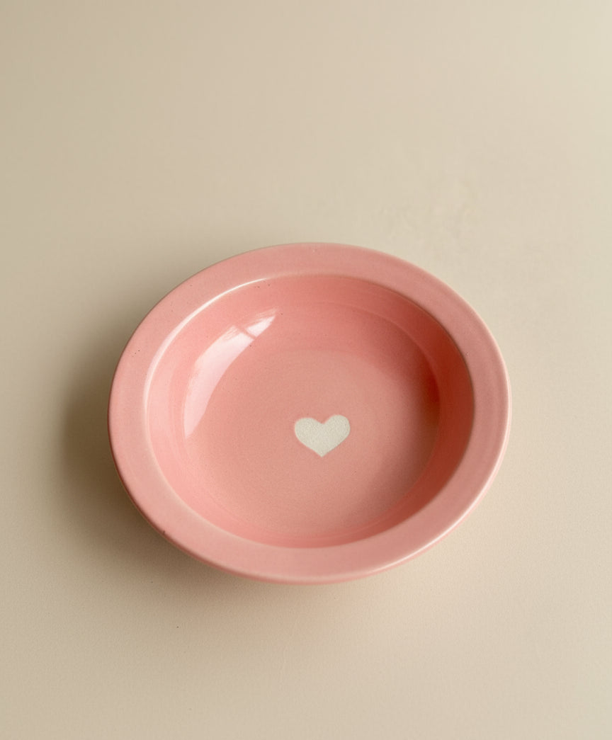 Pink bowl with a white heart on a beige background