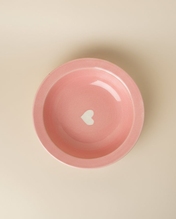 Pink bowl with a white heart on a beige background
