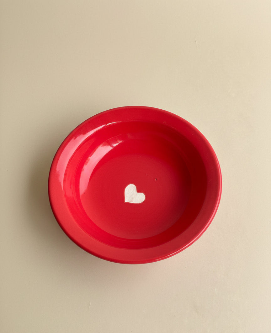 Red bowl with a white heart on a beige background