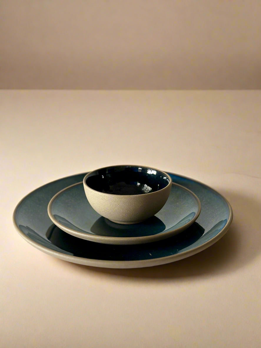 Set of ceramic plates and bowls on a white surface with a neutral background