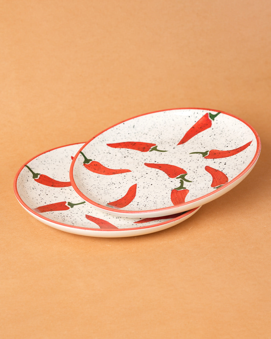 Set of two ceramic plates with red chili pepper design on a beige background