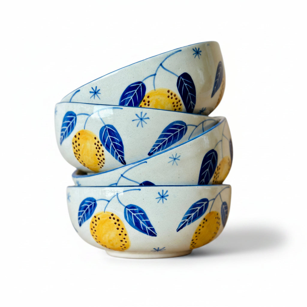 A stack of three ceramic bowls with a handpainted blue and yellow leafy pattern on a sky blue background.