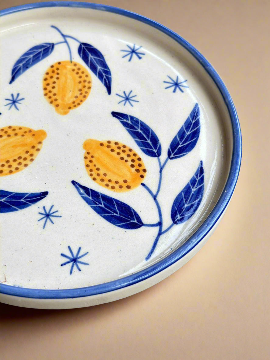 Decorative plate with lemon and leaf pattern on a concrete surface