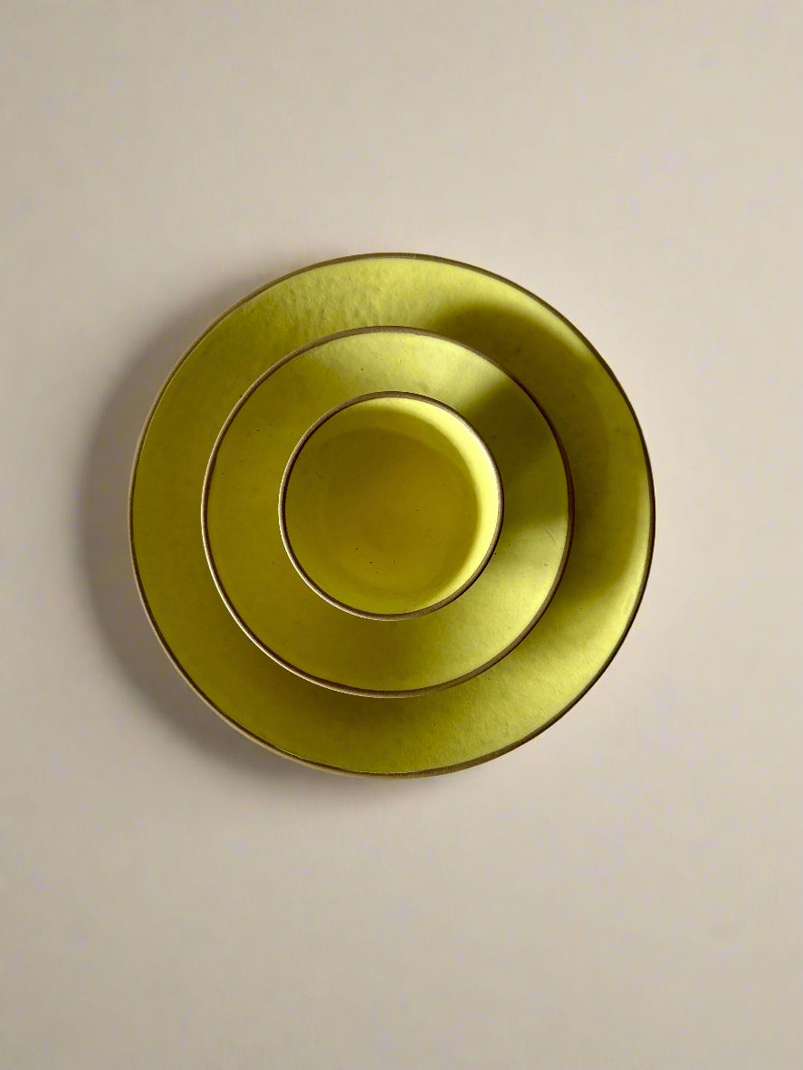 three yellow ceramic plates stacked on a textured white surface