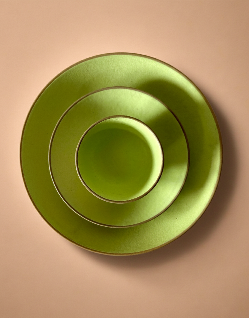 Set of three green ceramic plates stacked on a beige background