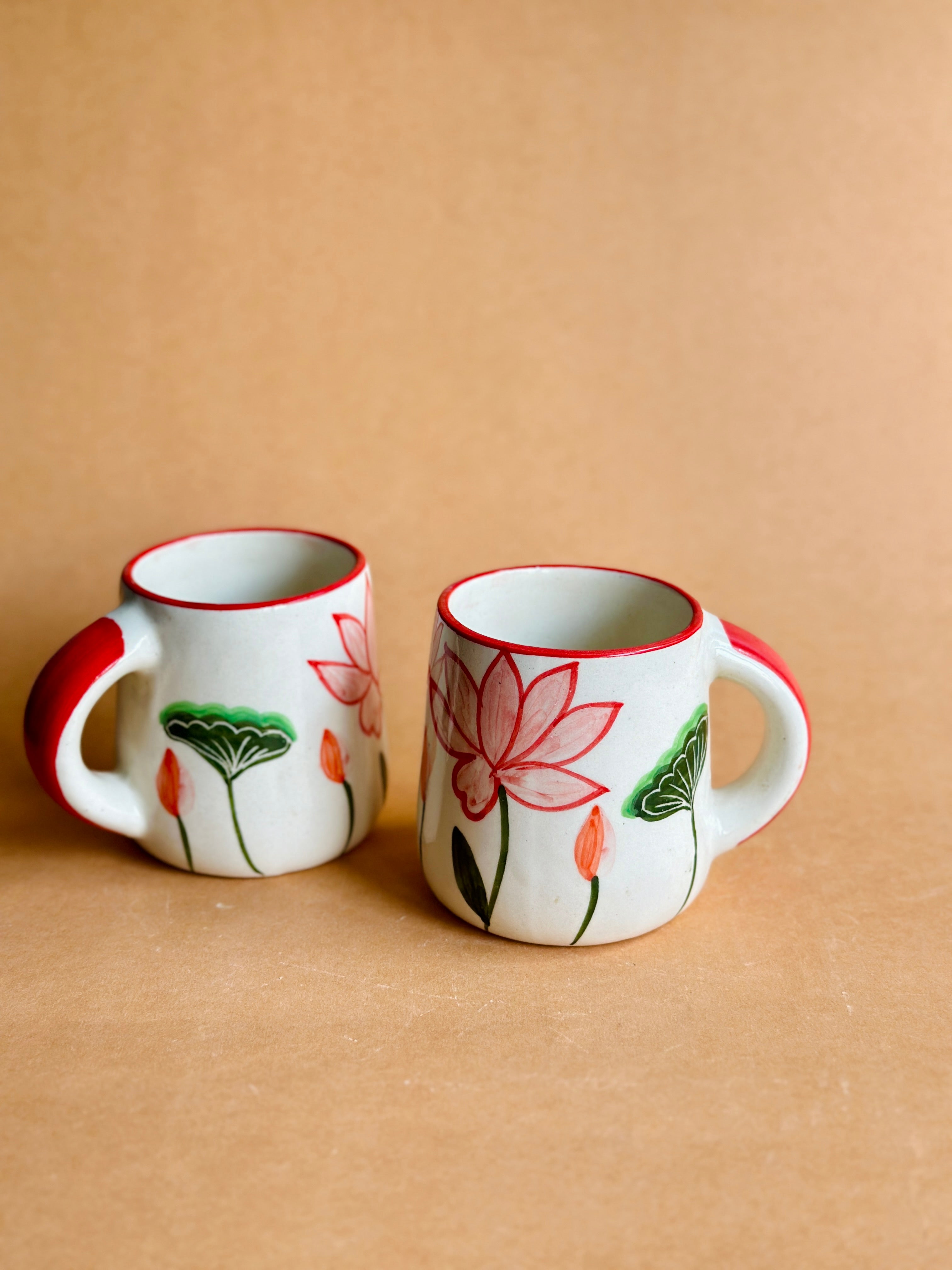 Two ceramic mugs with floral designs on a beige background