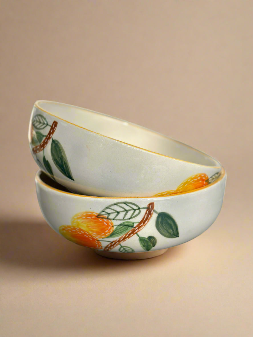 Two ceramic bowls with fruit design on a beige background