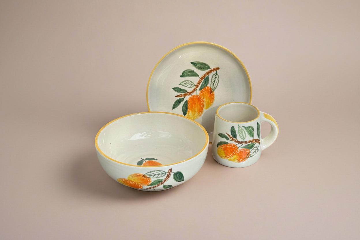 Ceramic dishes with orange and leaf design on a metallic surface