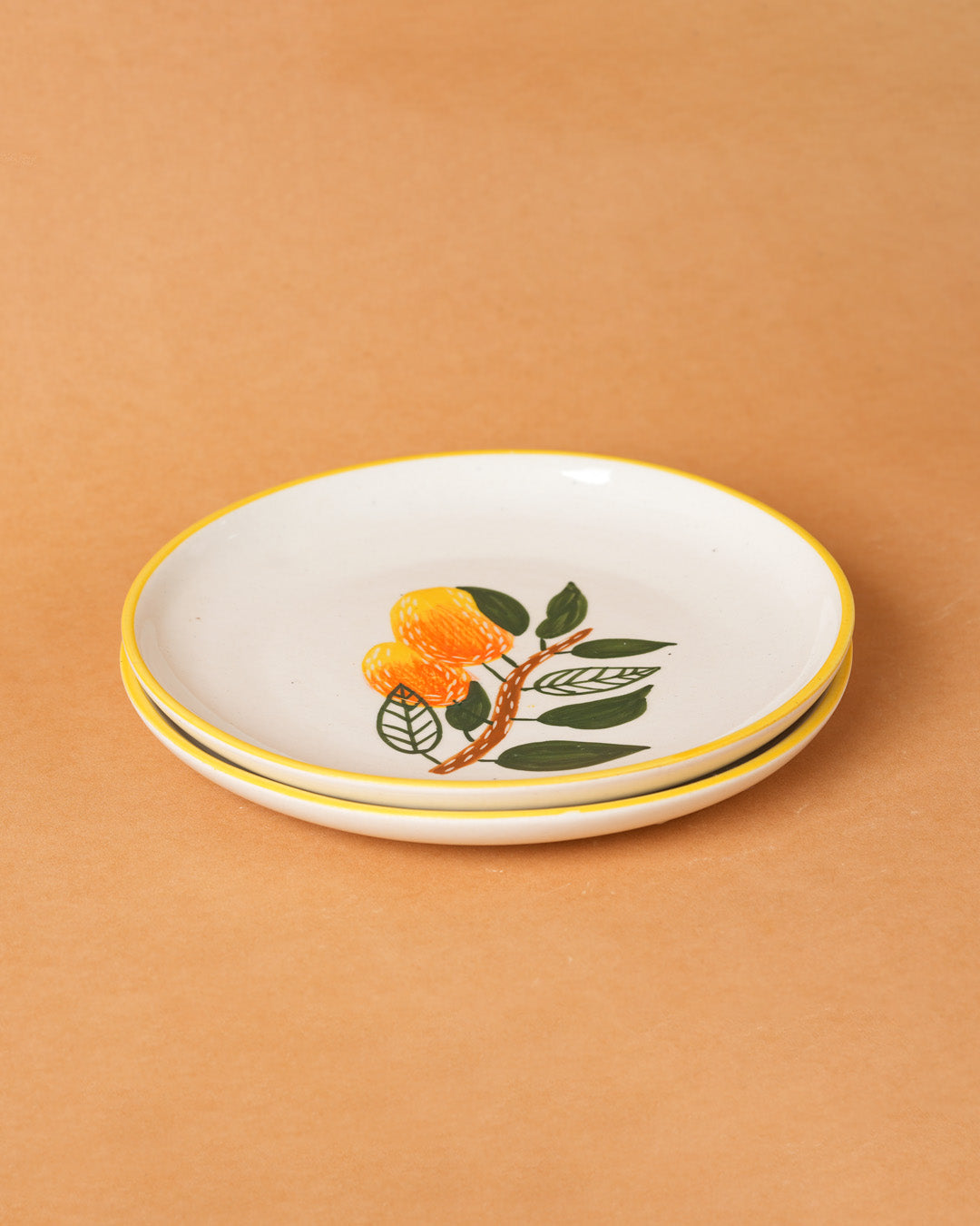 Stack of ceramic plates with floral design on a beige background