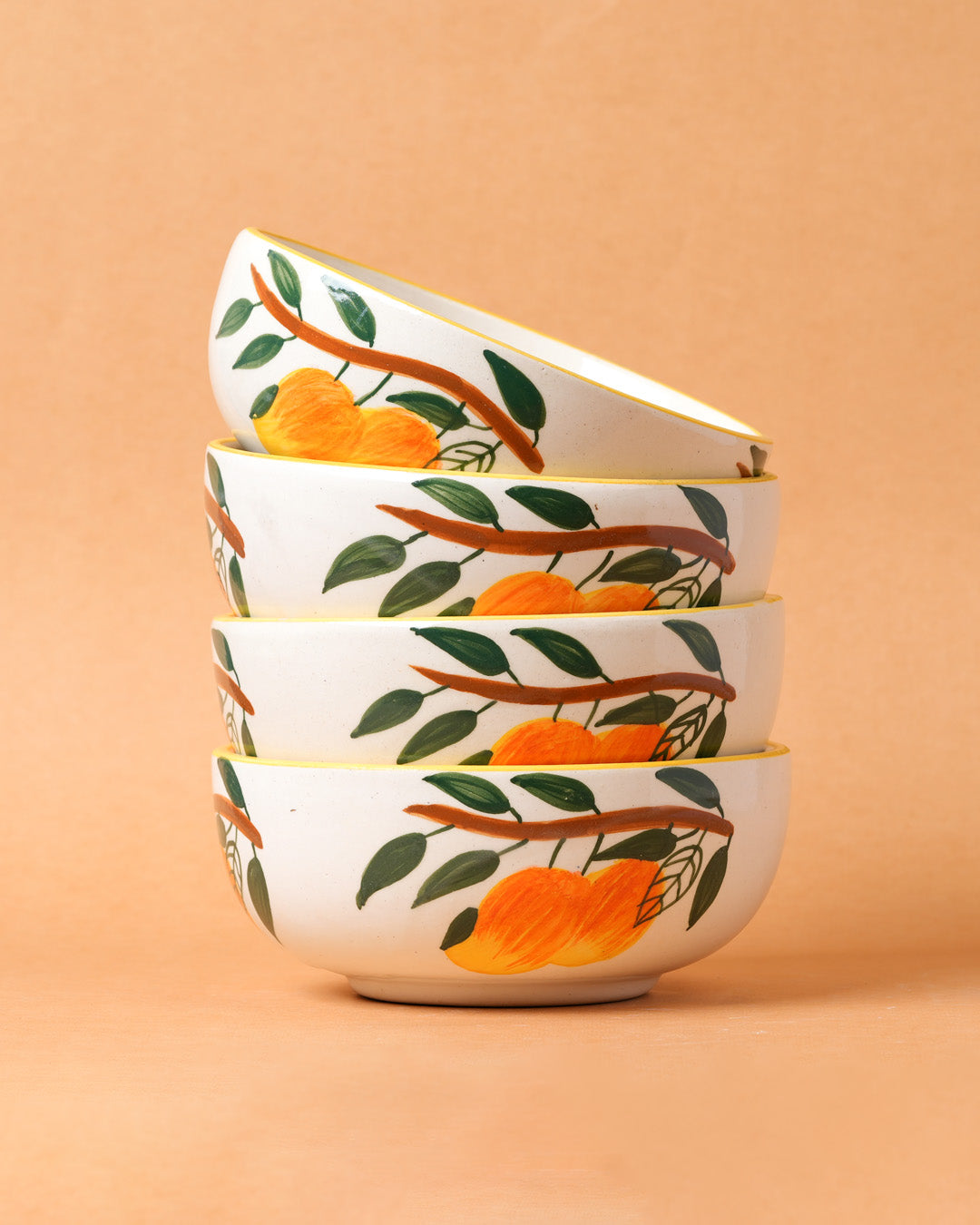Set of four ceramic bowls with orange and leaf design on a beige background