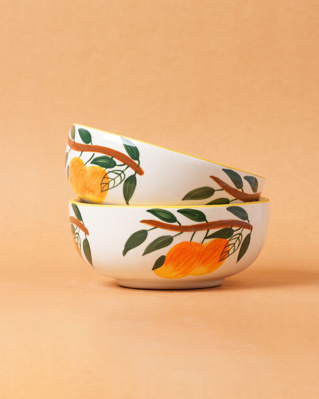 Two stacked ceramic bowls with fruit design on a beige background