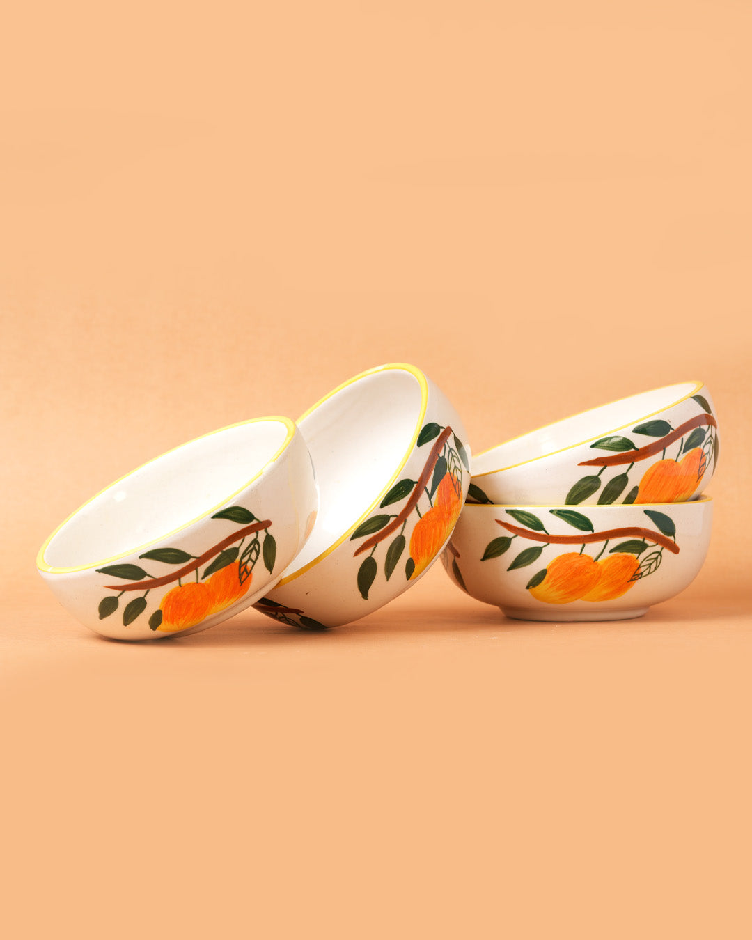 Set of ceramic bowls with orange and leaf design on a beige background