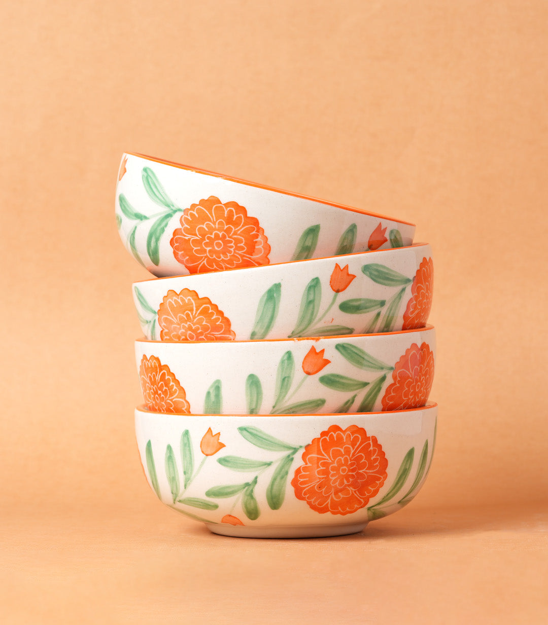 Stack of four ceramic bowls with floral pattern on a beige background