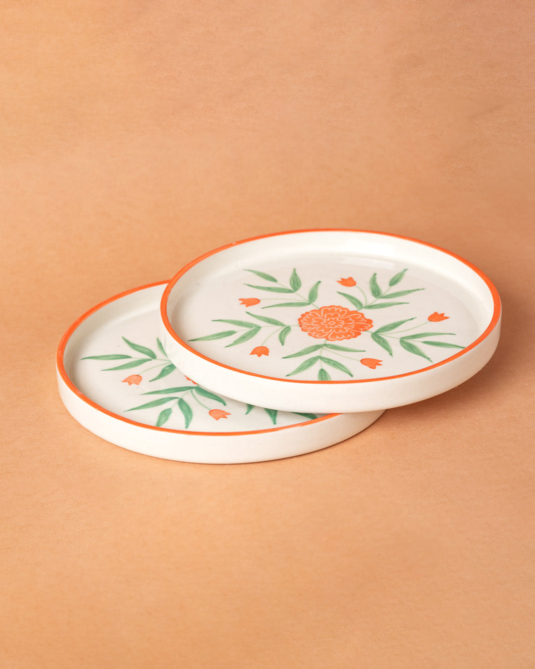 Two ceramic plates with floral designs on a beige background