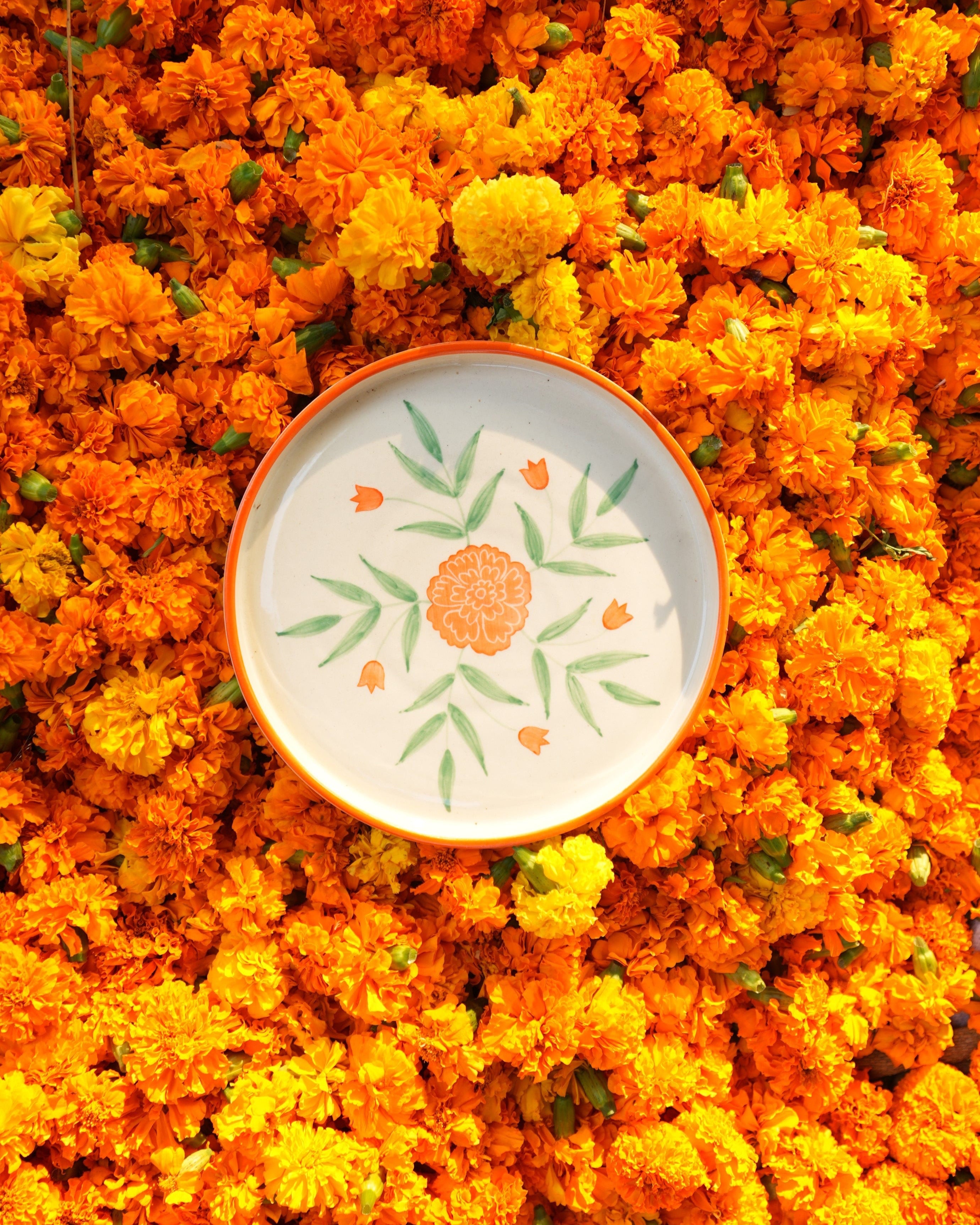 Decorative plate with floral design on a bed of orange marigold flowers