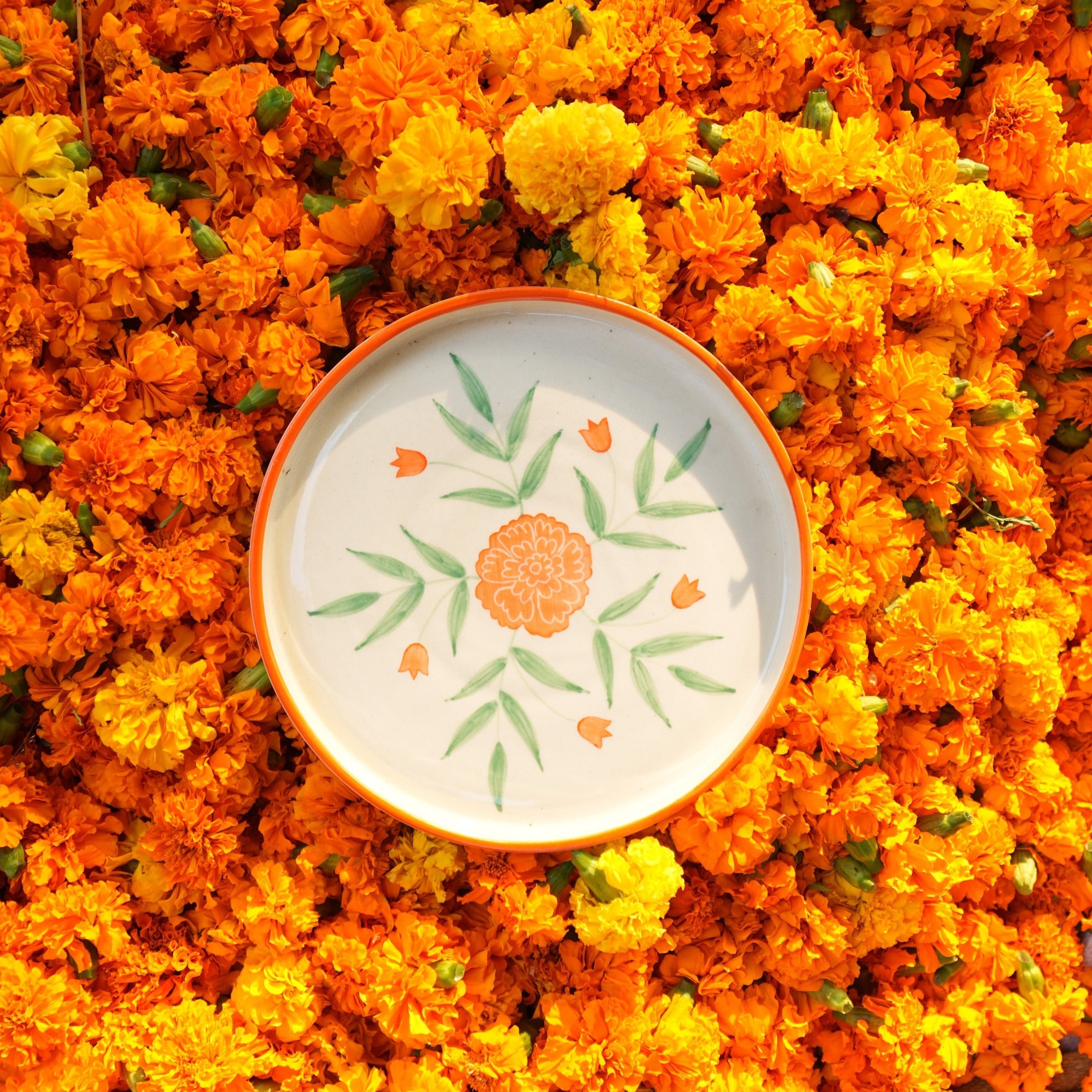 Decorative plate with floral design on a bed of orange marigold flowers
