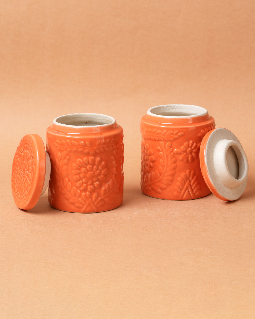 Two orange ceramic jars with textured design on a beige background