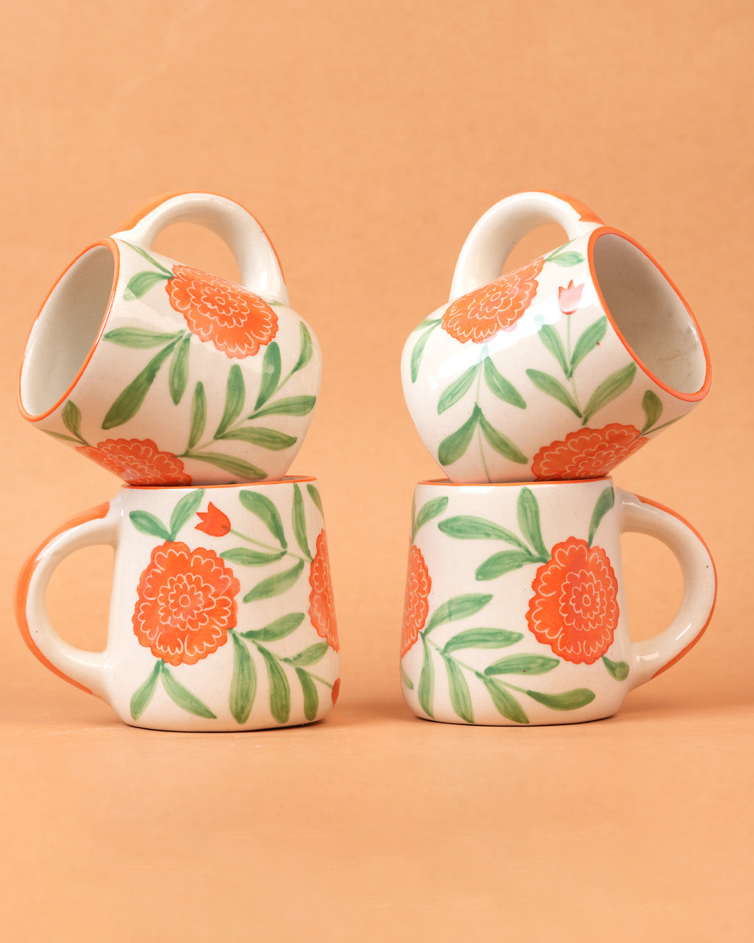 Four ceramic mugs with floral design on a peach background