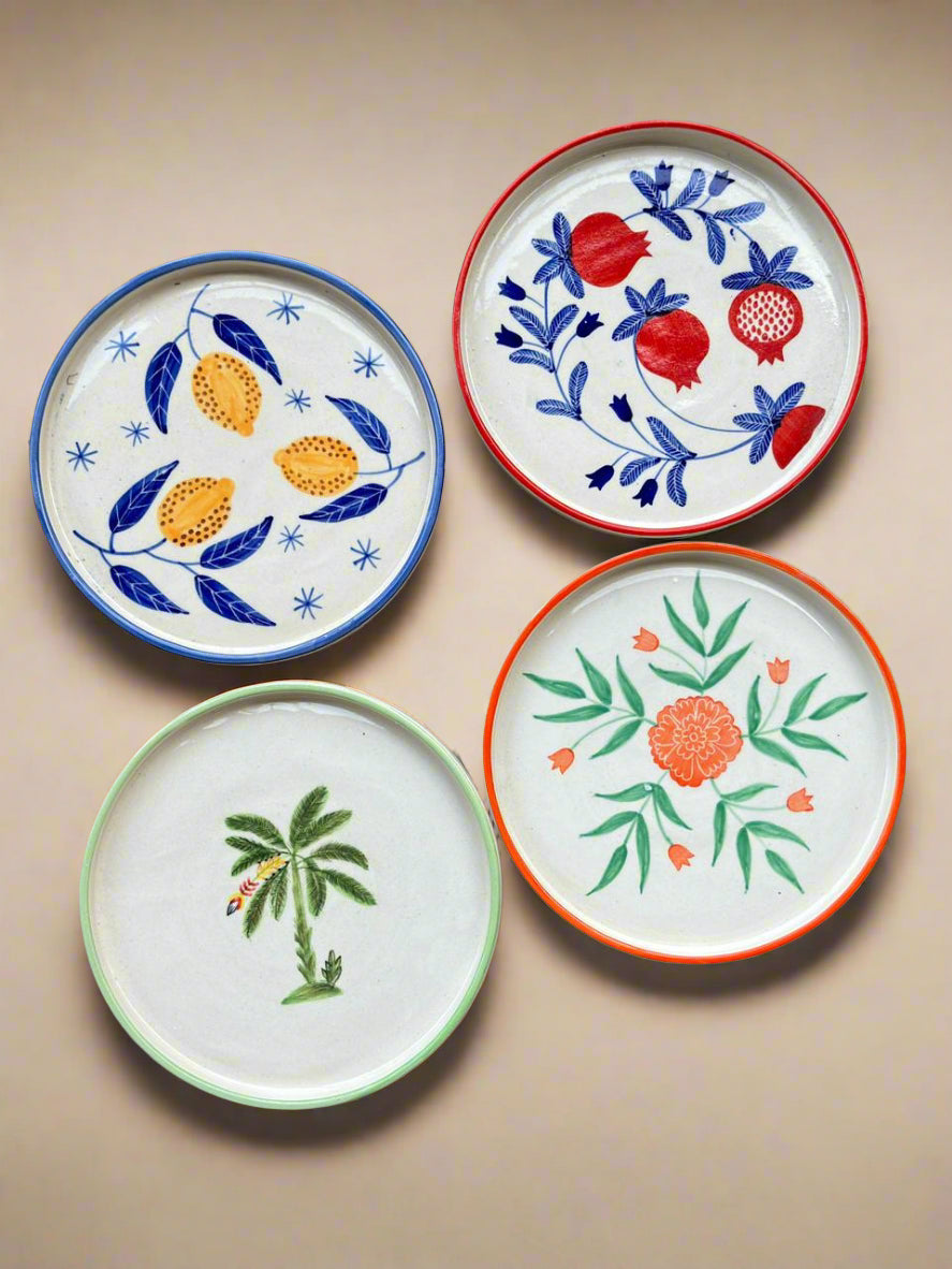 Four decorative plates with floral and botanical designs on a beige background