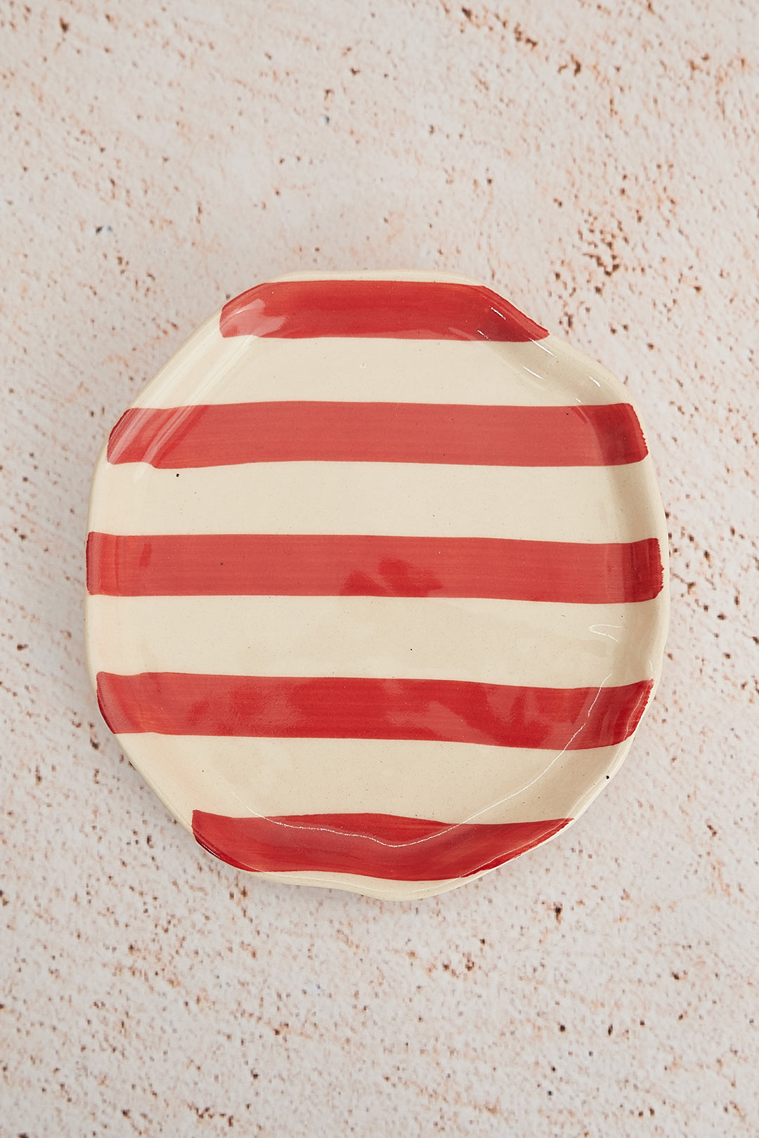 Red and white striped ceramic plate on a textured beige surface