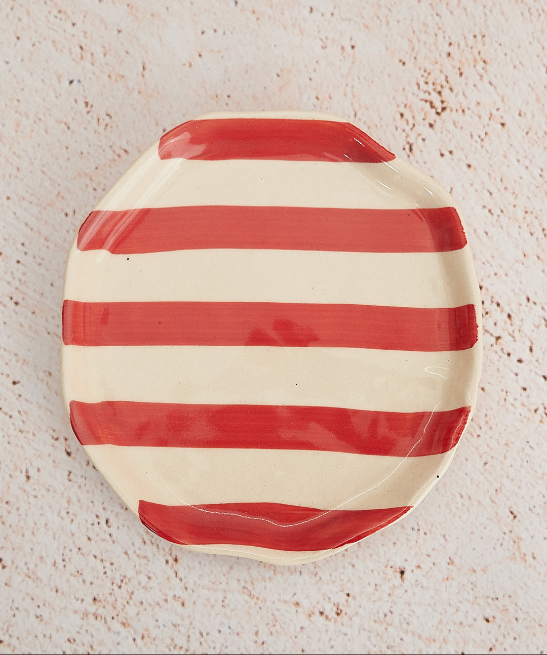 Red and white striped ceramic plate on a textured beige surface