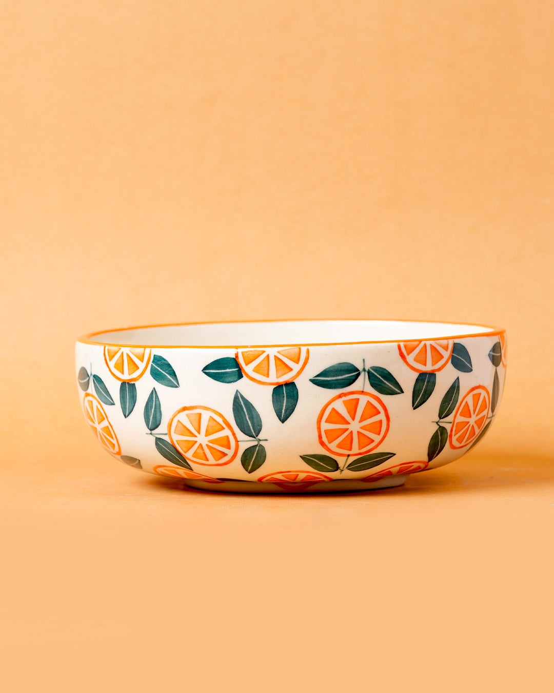 Ceramic bowl with orange and leaf pattern on a beige background