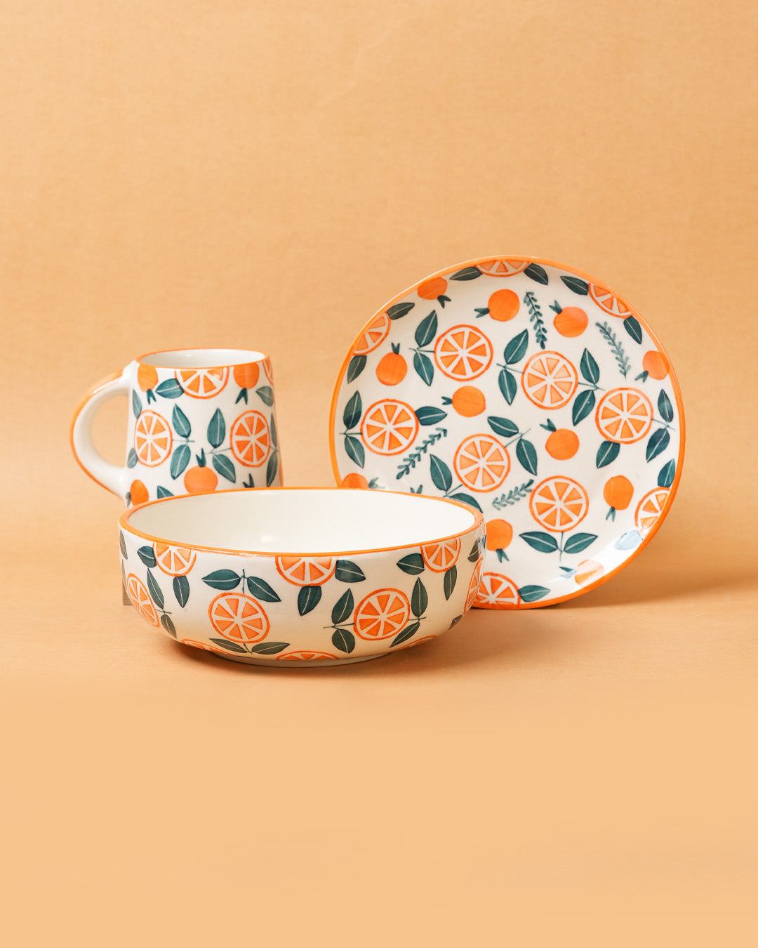 Ceramic tableware set with orange and leaf pattern on a beige background