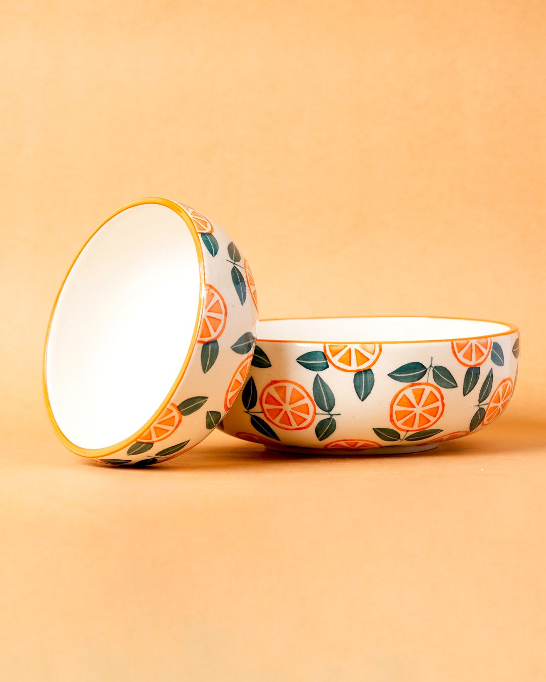 Ceramic bowl with orange and leaf pattern on a beige background