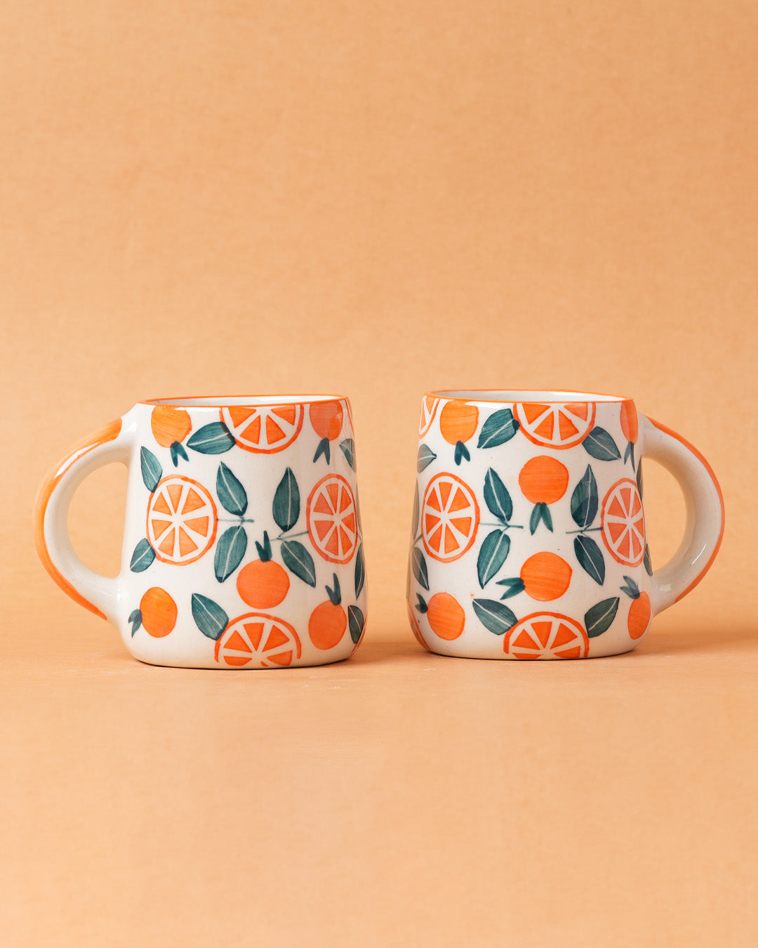 Two mugs with orange and green pattern on a beige background