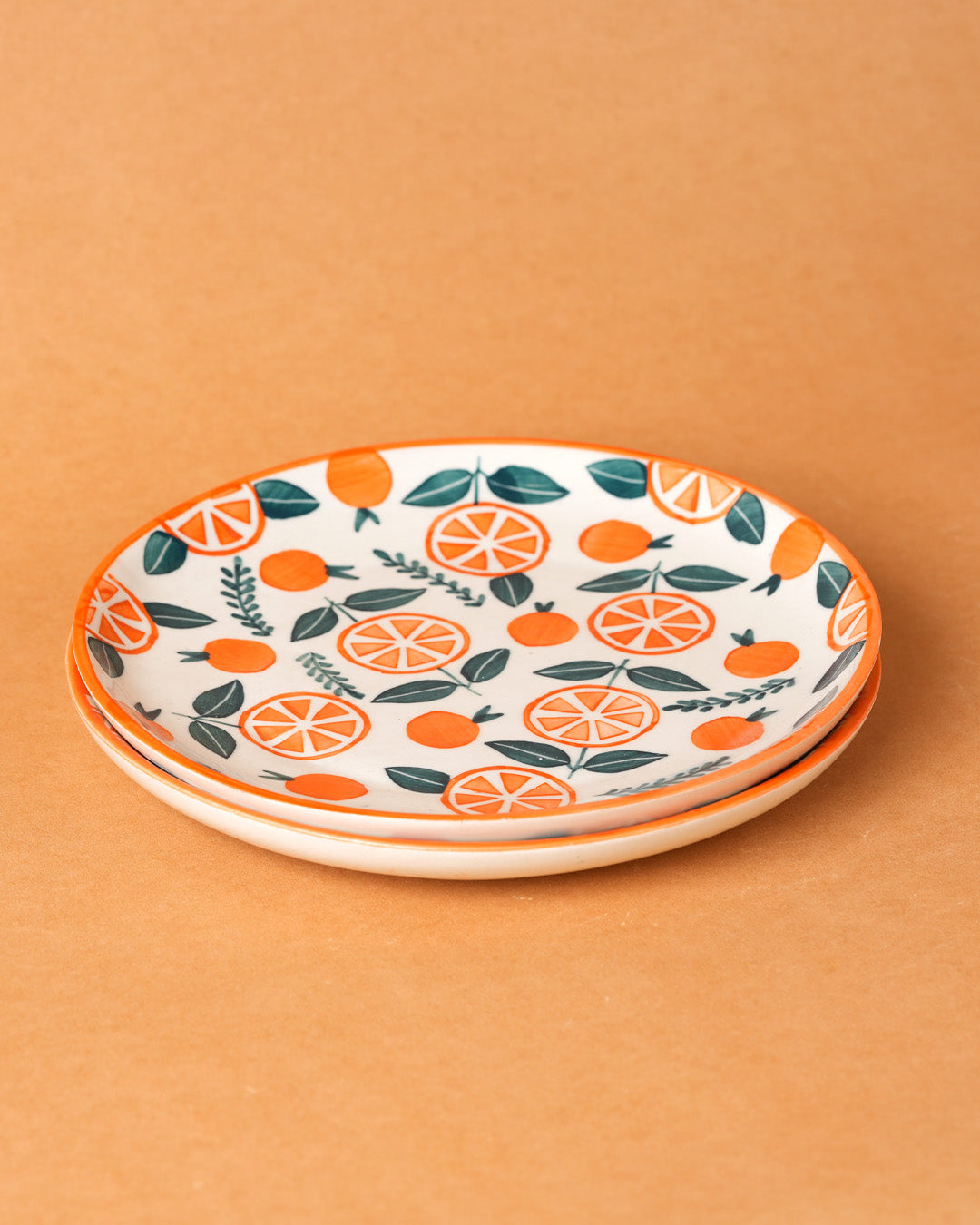 Two ceramic plates with orange and leaf pattern on an orange background