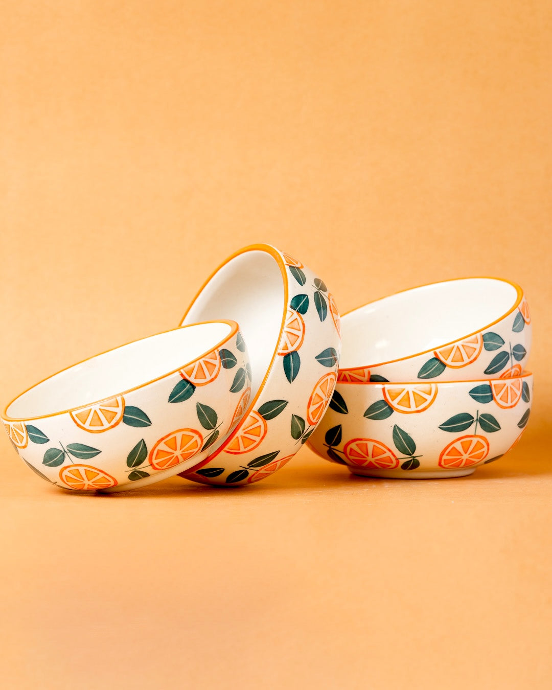 Three ceramic bowls with orange and leaf pattern on a beige background