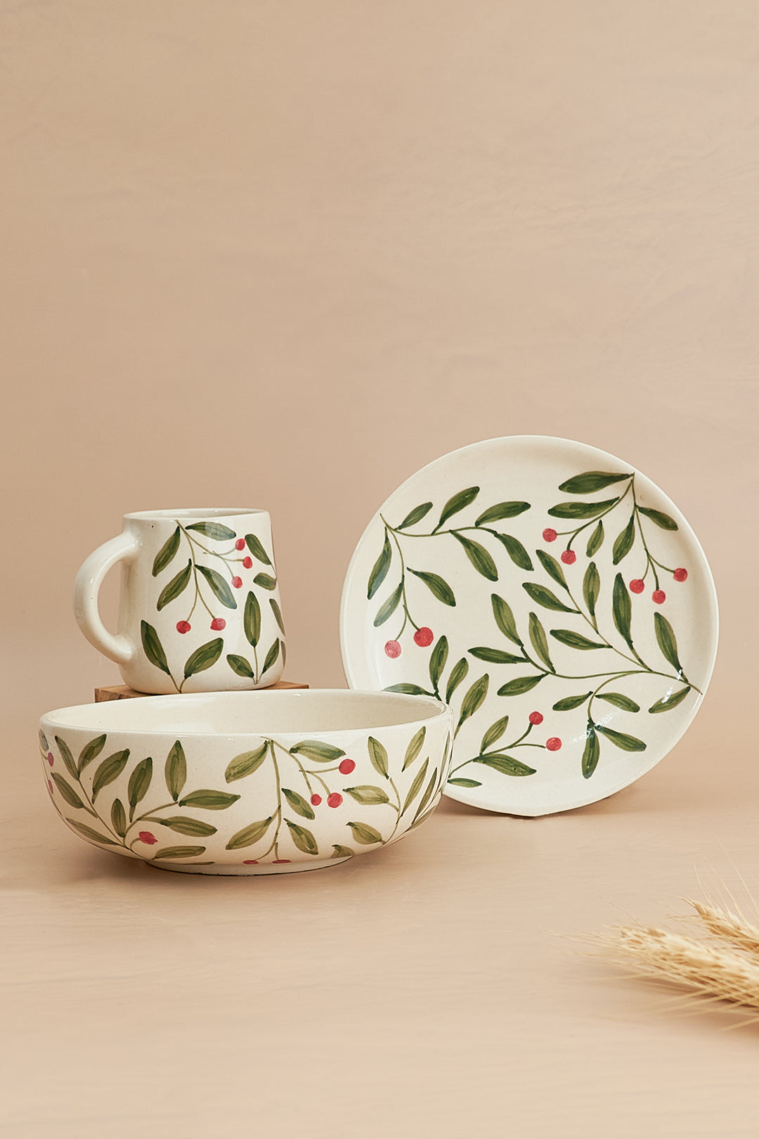 A set of breakfast dishes featuring a floral pattern in green and white, including a bowl, a plate, and a mug, displayed against a neutral background.