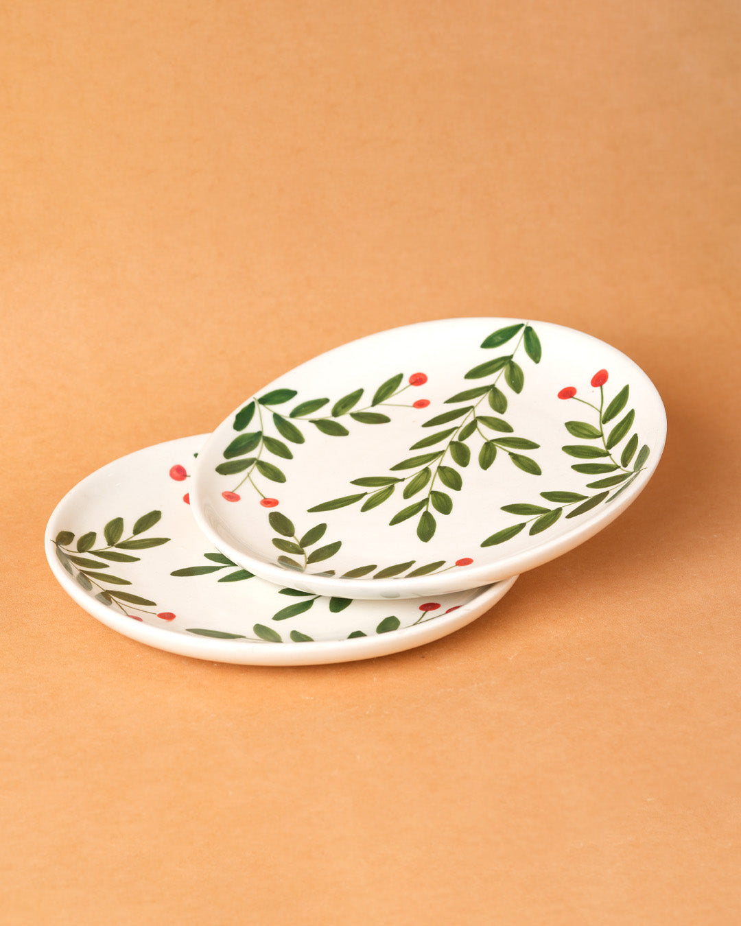 Two ceramic plates with leaf pattern on a beige background