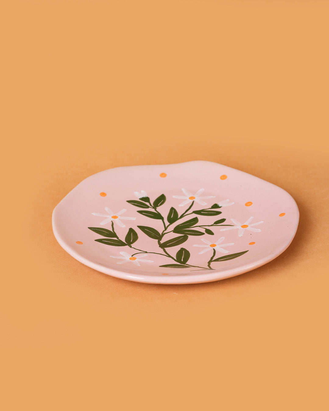 Pink plate with green leaf design on a beige background