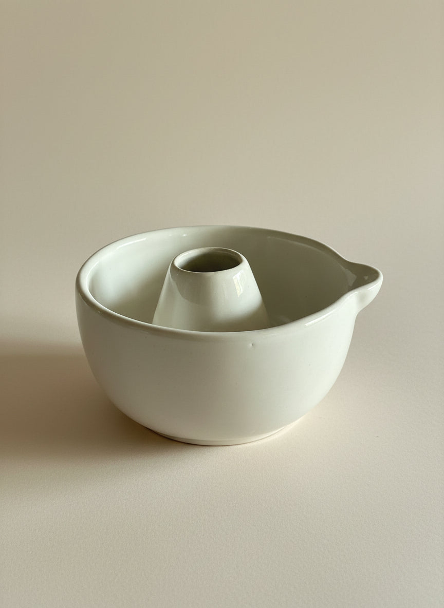 White ceramic bowl with a smaller cylindrical container inside on a beige background