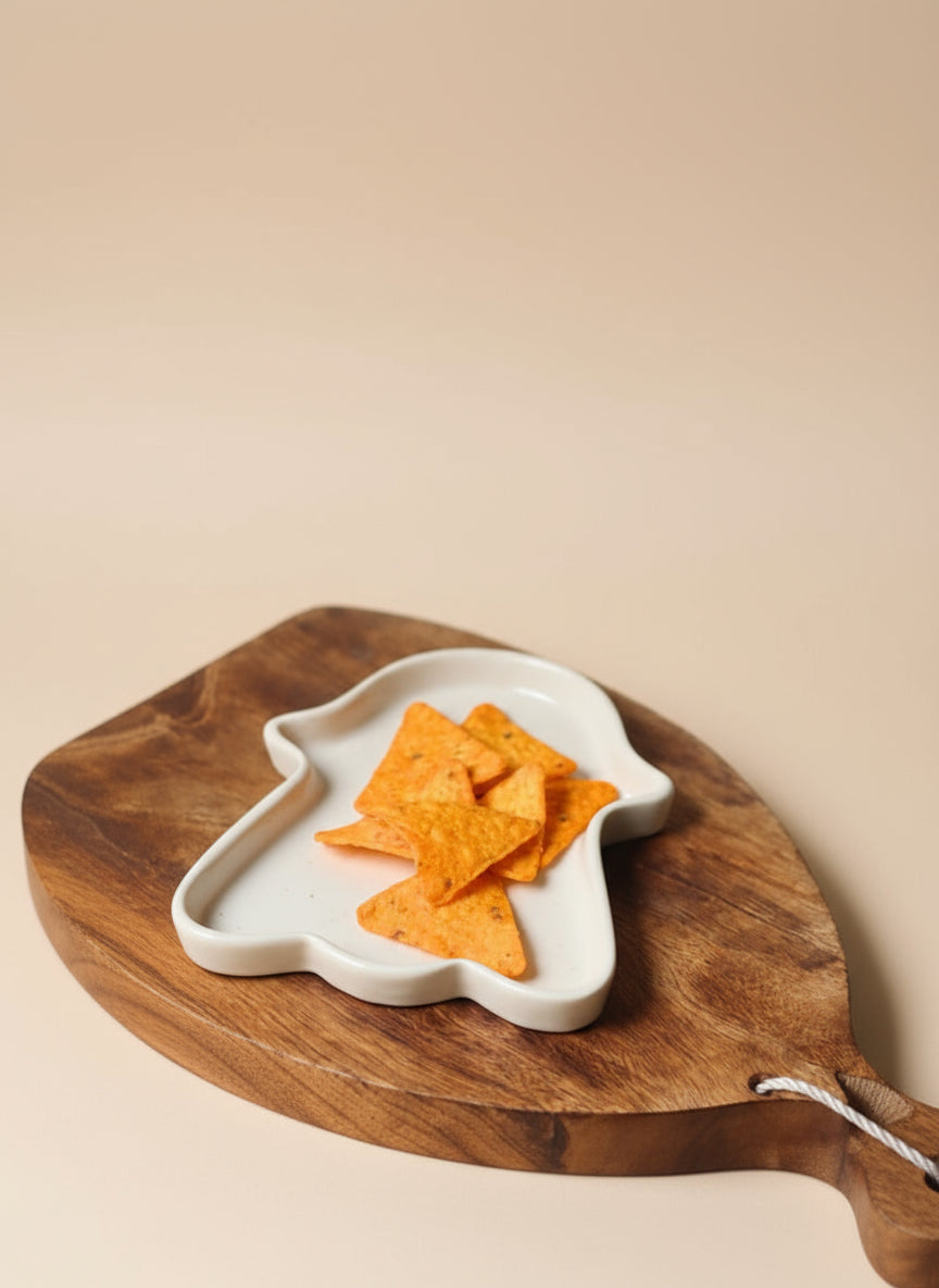 Wooden serving board with a white dish holding tortilla chips on a beige background